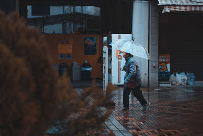 Side view of woman walking on street during rainy season