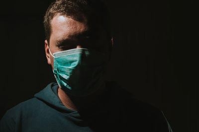 Close-up portrait of man with mask on black background