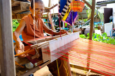 Close-up of senior woman weaving on equipment