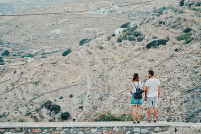 Rear view of couple standing on wall against land