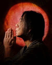 A man prays and expresses his gratitude with joined palms with a red circle in the background.