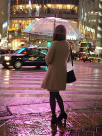 Rear view of woman standing on street at night