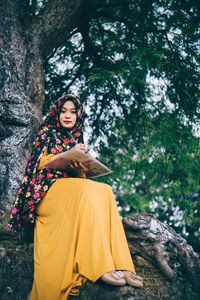 Young woman sitting on tree trunk