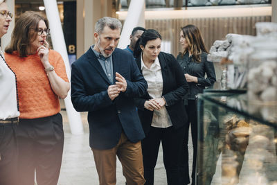 Business people looking at breads in display window at conference