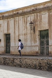 Side view of woman walking against buildings