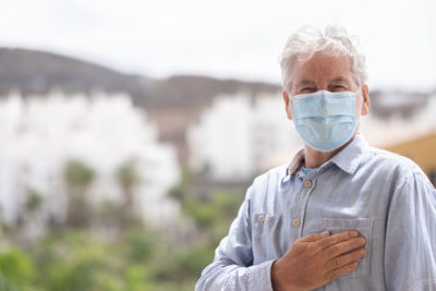 Portrait of senior man wearing mask standing outdoors