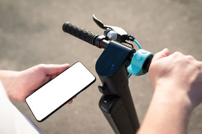 Hands of a person using a smartphone mobile application to pay for renting an electric scooter 