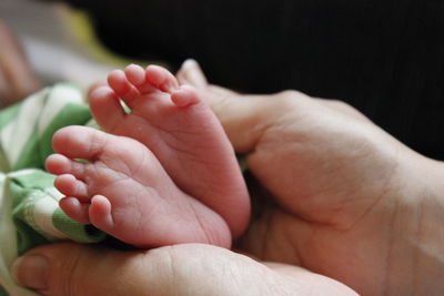 Cropped hands of mother touching feet of baby