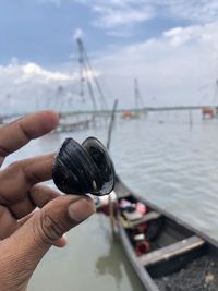 Cropped hand holding clamp against boat at beach