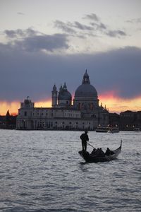 Gondolier in grand canal against santa maria della salute during sunset