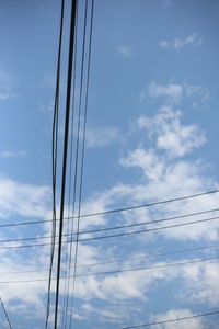 Low angle view of electricity pylon against blue sky