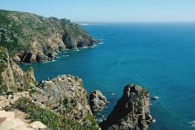 Scenic view of sea by mountains during sunny day