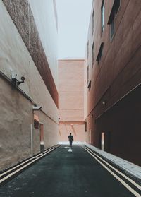 Man walking on road along buildings