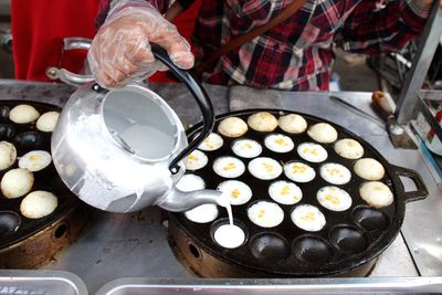Midsection of vendor preparing coconut pancake