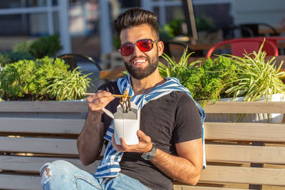 Young man drinking glass sitting outdoors