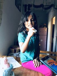 Portrait of smiling girl sitting on table at home