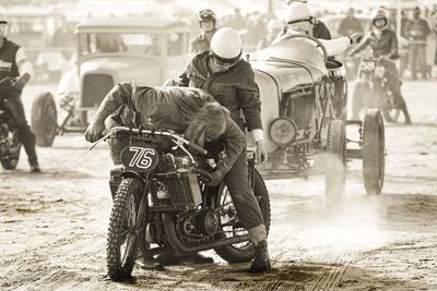 Rear view of people riding motorcycle on road