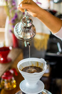 Cropped hand preparing coffee at cafe