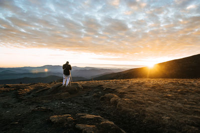 Rear view of woman photographing sunset on mountain