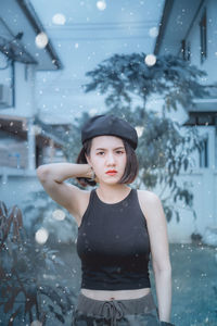 Portrait of young woman standing against buildings during winter