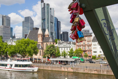 Padlocks on metallic bridge against boat in lake at city