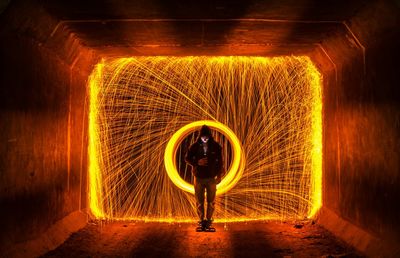 Man standing against illuminated wire wool at night