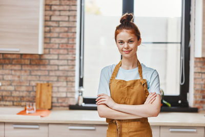 Portrait of smiling young woman standing against wall