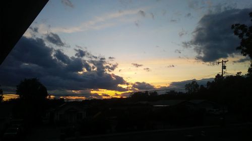 Silhouette houses against sky during sunset