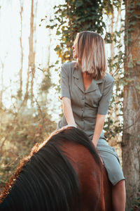 Woman sitting on horse in forest