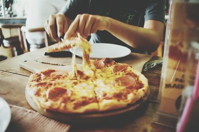 Close-up of hand holding pizza in plate