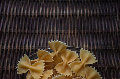 High angle view of raw farfalle pasta on wicker