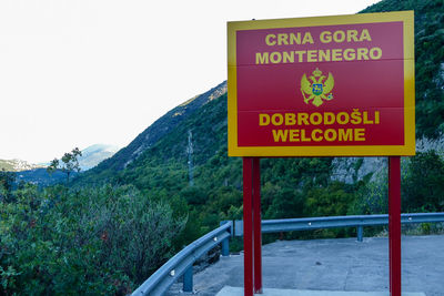 Information sign by road against sky