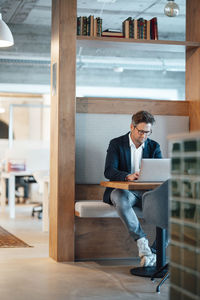 Mature businessman using laptop sitting at desk in office