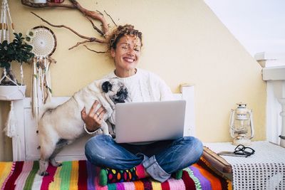 Portrait of woman with dog sitting in smart phone