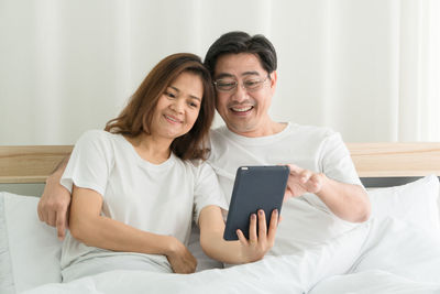 Portrait of a smiling young man using laptop on bed