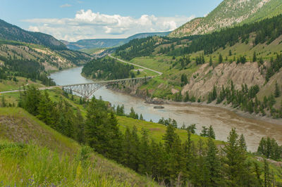 Scenic view of river by mountains against sky