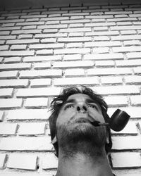 Portrait of young man looking away against brick wall