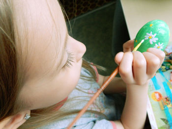 High angle view of girl painting on easter egg