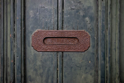 Metal letter box slot in a wooden door.