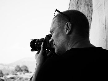 Close-up of man photographing against sky