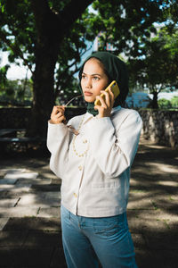 Portrait of young woman standing against trees