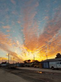 Cars moving on road against cloudy sky during sunset