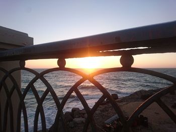 Silhouette bridge over sea against clear sky during sunset