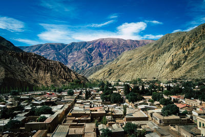 Aerial view of townscape and mountains against sky