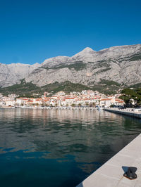 Scenic view of lake by mountains against clear blue sky
