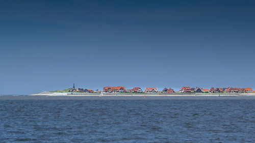 Sea by buildings against clear blue sky