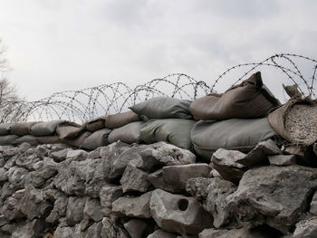 Stone wall by rocks against sky