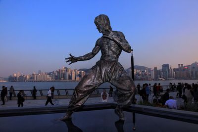 Statue of people in city against clear sky