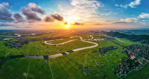 High angle view of green landscape against sky during sunset