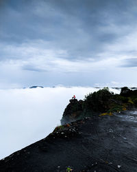 Man standing on rock against sky